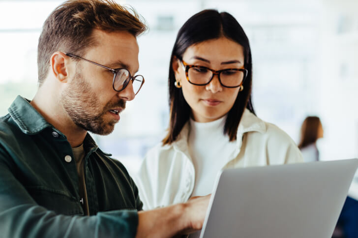 Woman and man in glasses looking at a computer screen together